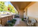 Inviting covered front porch with chairs, plants, and decorative brick accents at 13823 N 99Th Dr, Sun City, AZ 85351