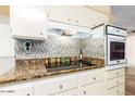 Well-lit kitchen with stainless steel appliances, granite countertops, and stylish tile backsplash at 13823 N 99Th Dr, Sun City, AZ 85351