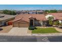 An aerial of a single-story home with a terracotta roof, three-car garage, and lush green landscaping at 1506 W Laurel Ave, Gilbert, AZ 85233
