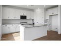 Modern kitchen with white cabinetry, granite countertops, stainless steel appliances, and wood flooring at 24249 W Agora Ln, Buckeye, AZ 85326