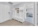 A clean and organized mudroom with a white storage bench, tile flooring, and entry to the bedroom at 2820 E Surrey Ave, Phoenix, AZ 85032