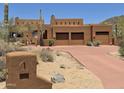 Stunning desert home featuring a three-car garage, earthy stucco exterior, and native landscaping at 7728 E Mary Sharon Dr, Scottsdale, AZ 85266