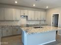 Open-concept kitchen boasts gray cabinets, granite countertops, and an island perfect for food prep and entertaining at 9963 W Verde Ln, Avondale, AZ 85392