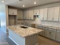 Spacious kitchen with gray cabinets, granite countertops, and a large center island with a sink at 9963 W Verde Ln, Avondale, AZ 85392