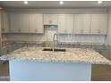 Bright kitchen featuring gray cabinets, granite countertops, and a large island with seating and a sink at 9963 W Verde Ln, Avondale, AZ 85392