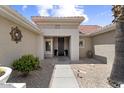 Inviting front entry with a covered porch, desert landscaping, and an attractive metal front door at 15501 W Camino Real Way, Surprise, AZ 85374