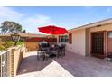 Cozy backyard patio with a red umbrella, grill, and outdoor seating, ideal for entertaining guests at 15614 N Lakeforest Dr, Sun City, AZ 85351