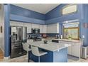 Modern kitchen with stainless steel appliances, a blue island and lots of natural light at 16396 W Fillmore St, Goodyear, AZ 85338