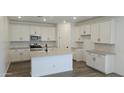 Bright kitchen with white cabinets, modern stainless steel appliances, island, and gray backsplash at 20645 N 226Th Ln, Surprise, AZ 85387