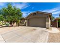 Lovely home featuring a two-car garage and desert landscaping, set under a bright blue sky at 42277 W Chisholm Dr, Maricopa, AZ 85138