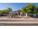 Inviting single-Gathering home featuring desert landscaping, stone accents, and a wide driveway with ample parking at 7590 W Firebird Dr, Glendale, AZ 85308