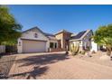 Charming home with desert landscaping, a brick driveway, a two-car garage, and solar panels on the roof at 7590 W Firebird Dr, Glendale, AZ 85308