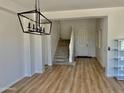 Open foyer with wood-look floors, staircase, and a modern light fixture at 7925 S 52Nd Dr, Laveen, AZ 85339