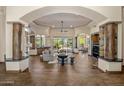 Open-concept living space with wood floors, stone pillars, a fireplace, and access to the outdoor spaces at 11717 E Estrella Ave, Scottsdale, AZ 85259