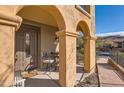 Inviting front porch with stone arches features seating and a decorative glass front door at 17874 N 93Rd Way, Scottsdale, AZ 85255