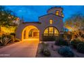 Inviting home exterior showcasing a unique turret design and well-lit entrance, perfect for evening enjoyment at 18283 N 93Rd St, Scottsdale, AZ 85255
