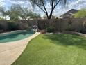 Private backyard features a refreshing pool with a rock waterfall feature, complemented by lush green turf and block fence at 2138 E Williams Dr, Phoenix, AZ 85024