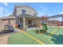 Backyard with covered patio, swing and play structure on artificial grass at 23693 W Grove St, Buckeye, AZ 85326