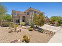 Charming two-story home featuring desert landscaping with cactus and blooming bushes, a red tile roof, and an arched entryway at 10415 E Rosemary Ln, Scottsdale, AZ 85255