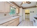 Traditional kitchen featuring light-colored cabinets, a double basin sink, and view into laundry room at 13631 N 103Rd Ave, Sun City, AZ 85351