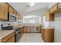 Functional kitchen with stainless steel appliances, light wood cabinets, and a view into an adjacent space at 16077 W Larkspur Dr, Goodyear, AZ 85338