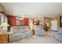 Spacious living room with comfortable seating, neutral carpet, and natural light from the adjacent rooms at 16527 W Blackhawk Ct, Surprise, AZ 85374