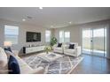 Open-concept living room with modern decor, large windows, and a sliding glass door for natural light at 17419 W Via De Luna Dr, Surprise, AZ 85387