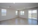 Bright and open living room with tile flooring, multiple windows, and a sliding glass door at 17419 W Via De Luna Dr, Surprise, AZ 85387