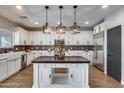 Gourmet kitchen boasts custom island, white cabinetry, stainless appliances, and stylish backsplash at 23420 N 121St Ave, Sun City, AZ 85373