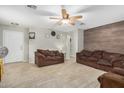 Cozy living room with tile floors, neutral paint, wood accent wall, and a ceiling fan at 24009 W Antelope Trl, Buckeye, AZ 85326