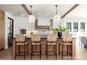 Bright kitchen with a large island, pendant lighting, hardwood floors, white cabinets, and seating for four at 3913 E Campbell Ave, Phoenix, AZ 85018