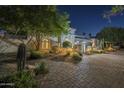 Beautiful night view of the home's facade with terracotta roof, lush plants and a brick-paved driveway at 7471 E Northern Ave, Scottsdale, AZ 85258
