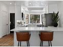 Modern kitchen with white cabinets, stainless steel appliances, quartz countertops and bar stool seating at 7760 E Pepper Tree Ln, Scottsdale, AZ 85250