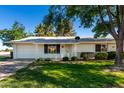 Charming single-story home with a well-manicured lawn, mature trees, and a welcoming front porch at 9863 W Country Club Ct, Sun City, AZ 85373
