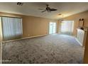 Spacious living room with plush carpet, ceiling fan, and sliding glass door at 1264 W 6Th Ave, Apache Junction, AZ 85120