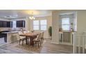 Open-concept dining area with a wooden table, white chairs, and a modern chandelier at 1624 N 77Th Gln, Phoenix, AZ 85035