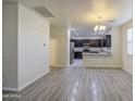 Spacious living room showcasing wood-look floors that lead into the dining and kitchen area at 1624 N 77Th Gln, Phoenix, AZ 85035