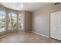 Bright bedroom with neutral walls, tiled floor, a closet, and large windows providing natural light and neighborhood views at 21675 N 61St Ave, Glendale, AZ 85308