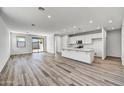 Spacious living area seamlessly connects to the kitchen with stylish flooring and ample natural light, perfect for modern living at 37535 W Patterson St, Maricopa, AZ 85138