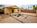 Spacious backyard with desert landscaping, a stylish fire pit, and a covered patio, ideal for entertaining guests at 44944 W Miramar Rd, Maricopa, AZ 85139