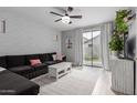 Cozy living room with a dark couch, brick accent wall, and sliding glass doors at 5253 E Hilton Ave, Mesa, AZ 85206