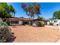 Inviting single-story home with a xeriscaped front yard, mature trees, and an RV parked on the driveway at 8238 E Jackrabbit Rd, Scottsdale, AZ 85250