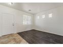 Bright living room featuring wood floors, three large windows, and a crisp white door at 11016 W Griswold Rd, Peoria, AZ 85345