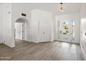 Bright foyer showcasing wood-look flooring, a modern front door with sidelights, and an arched doorway at 13631 N 70Th Dr, Peoria, AZ 85381