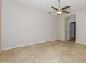 Cozy bedroom with neutral walls, tile floors, ceiling fan, and a doorway leading to another room at 2475 E Vermont Dr, Gilbert, AZ 85295