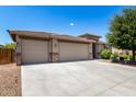 Well-manicured front yard featuring a three-car garage and lush, mature trees and shrubbery at 35654 N Vidlak Dr, San Tan Valley, AZ 85143