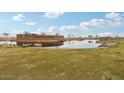 Scenic view of the Amarillo Creek community entrance with a picturesque pond and lush greenery at 47702 W Cansados Rd, Maricopa, AZ 85139