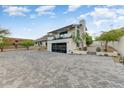 Spacious driveway featuring stylish brickwork, leading to a modern home with a balcony and glass garage door at 5801 E Surrey Dr, Cave Creek, AZ 85331
