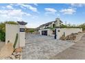 Gated front yard with modern brickwork, desert landscaping, and a contemporary home with a glass garage door at 5801 E Surrey Dr, Cave Creek, AZ 85331