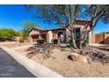 Single-story home with stone accents, a brick driveway, a charming front porch, and mature desert landscaping at 7939 E Stonecliff Cir, Mesa, AZ 85207